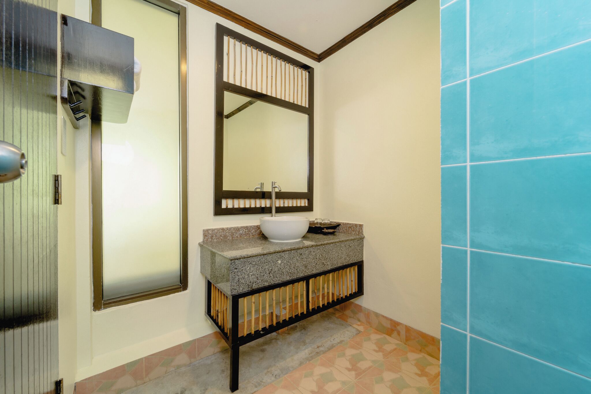 Un baño con lavamanos, espejo y piso de baldosas.