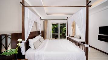 Una cama con dosel, ropa de cama blanca, una mesita de noche con un jarrón de flores y vistas al exterior a través de un ventanal.