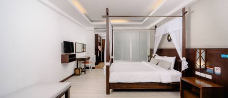 A hotel room with a four-poster bed, a bedside table, a bench, a TV mounted on the wall, and a wardrobe.
