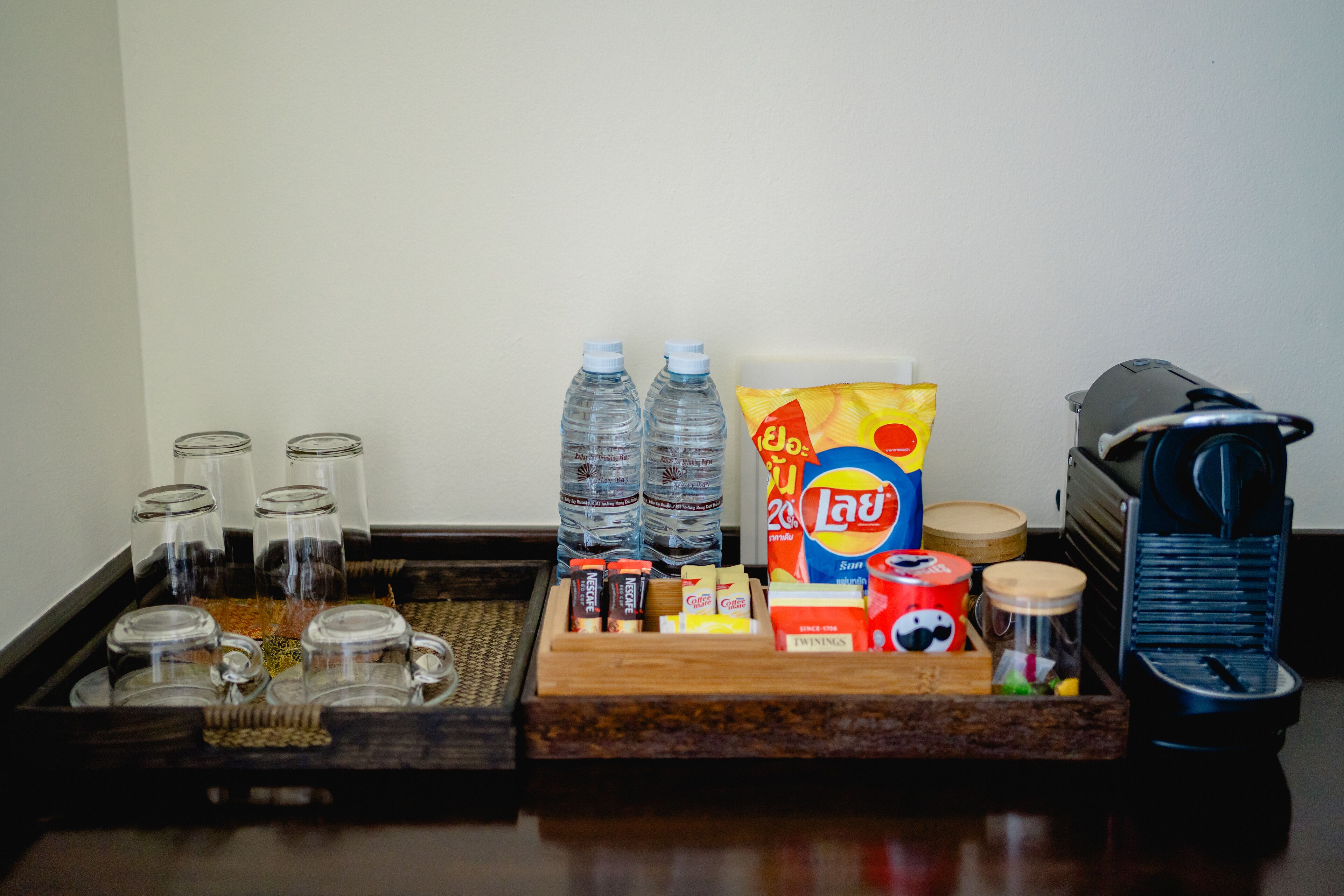 A tray with various items including water bottles, a coffee maker, and a bag of snacks.
