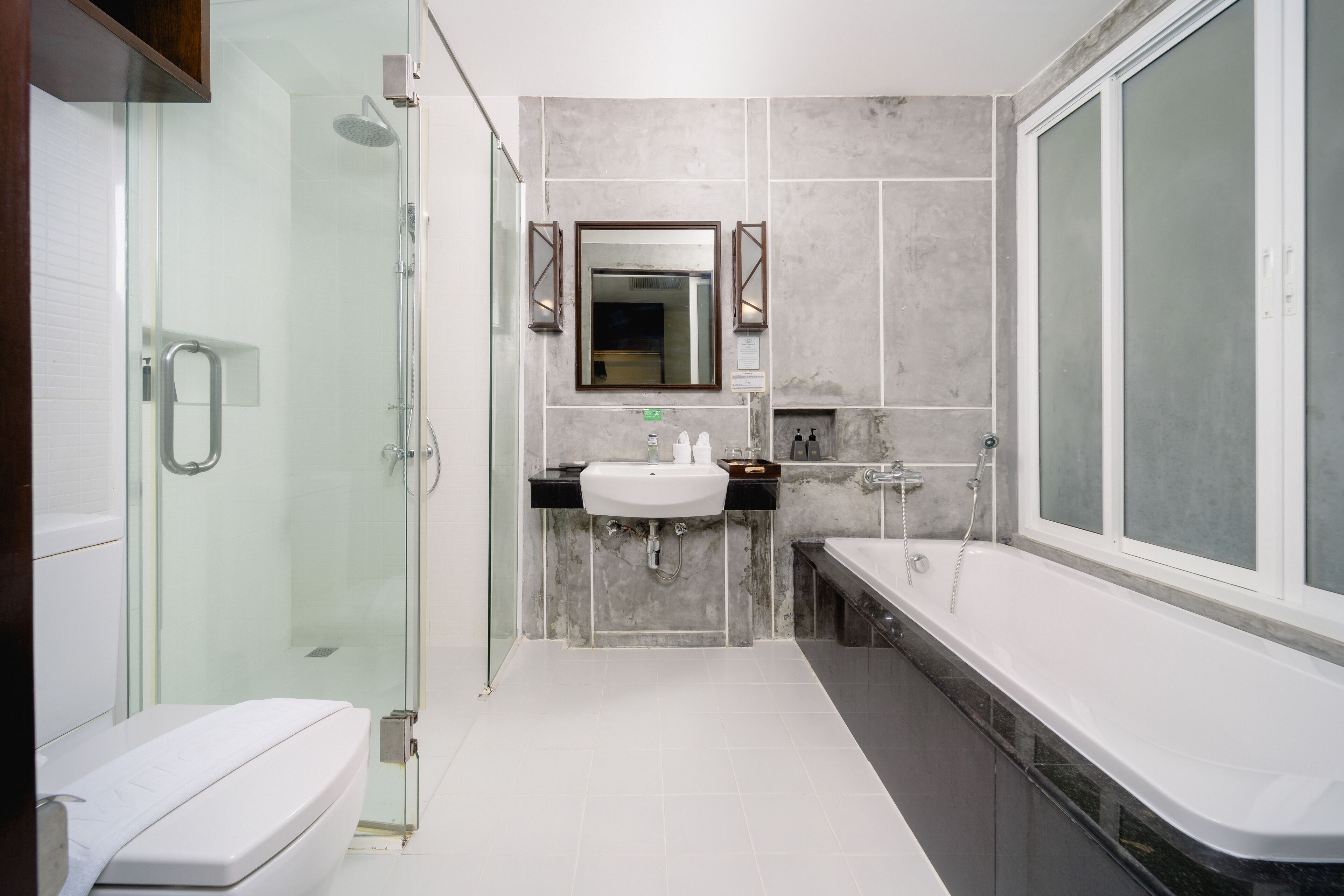 A modern bathroom with a glass-enclosed shower, a white sink, a large mirror, and a bathtub.