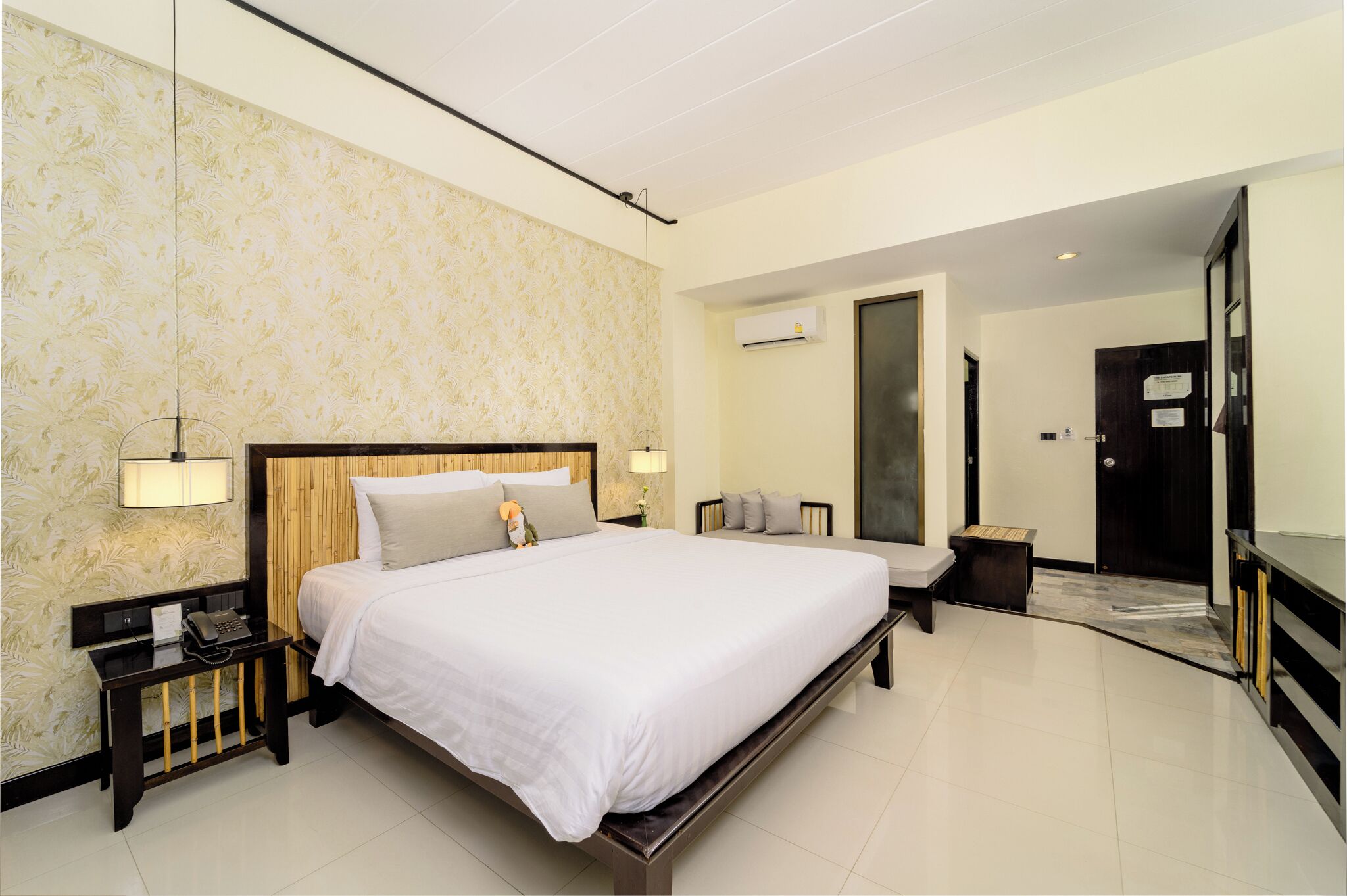 A modern hotel room with a large bed, bedside tables, a desk, and a wardrobe.