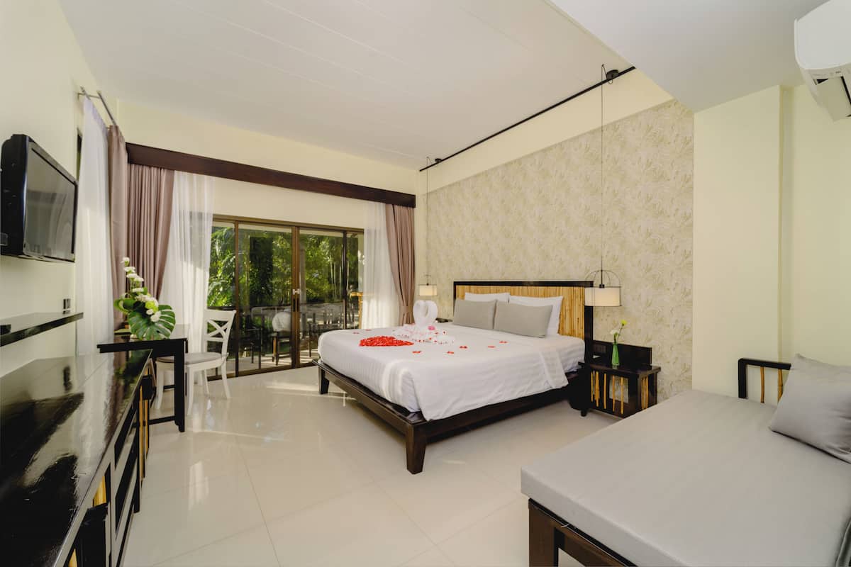 A hotel room with a bed, a desk, a chair, a TV, and a view of the outdoors.