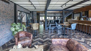 A modern interior with brick walls, leather sofas, and a herringbone floor pattern. - Best Western Amarys Hotel & Spa (Rambouillet)