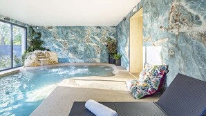 A spa area with a hot tub, seating, and a stone wall. - Best Western Amarys Hotel & Spa (Rambouillet)