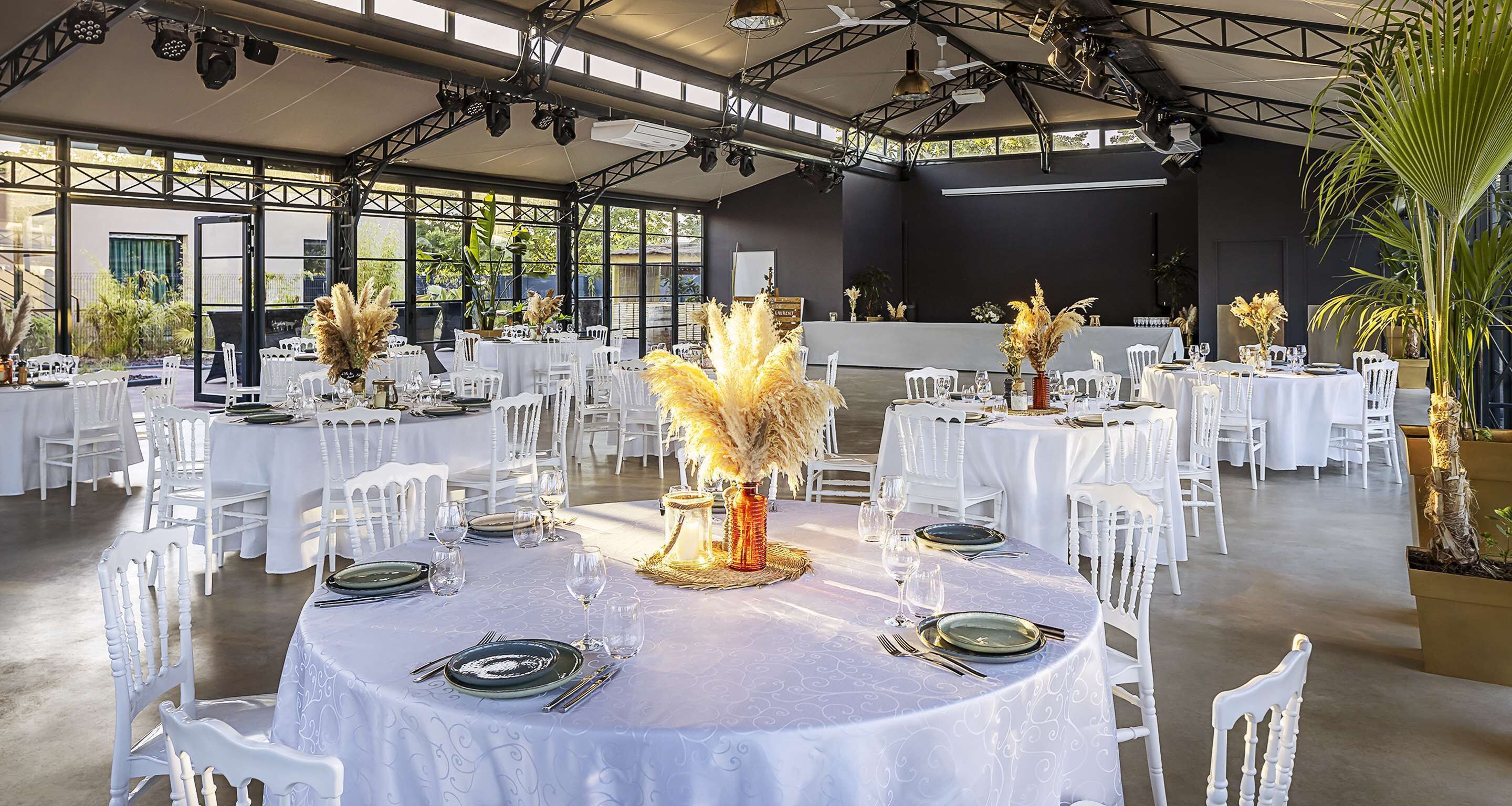 Un amplio espacio interior con mesas redondas dispuestas para comer, con manteles blancos y centros de mesa elegantes.