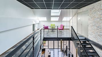 Un interior moderno con un entresuelo, una escalera y una pared de ladrillo.