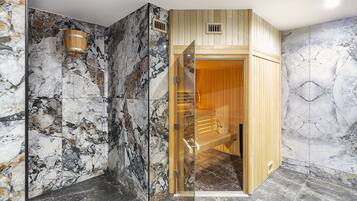 Un sauna avec un intérieur en bois, des murs en marbre et une porte en verre.