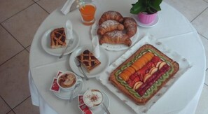 A breakfast table with croissants, a fruit tart, and coffee. - Residence Le Saline (Borgio Verezzi)