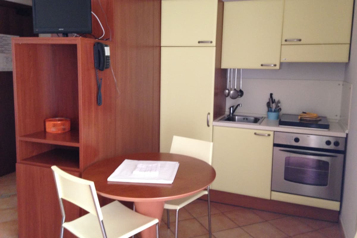 Une cuisine de taille réduite comprenant une table à manger, des chaises, une cuisinière et un évier.