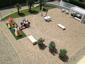 Un'area giochi con strutture ricreative e un'area salotto circolare con tavoli e panchine.