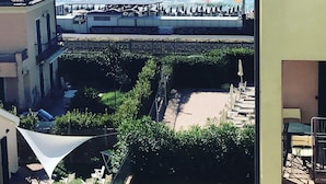 Un balcón con vistas al mar, un jardín cercado y un edificio con balcón.