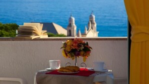 A balcony with a table set for breakfast, a book, and a view of the sea. - Residence Sant'Anna (Pietra Ligure)