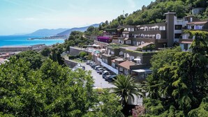 A coastal hotel with multiple balconies, a parking area, and lush greenery. - Residence Sant'Anna (Pietra Ligure)