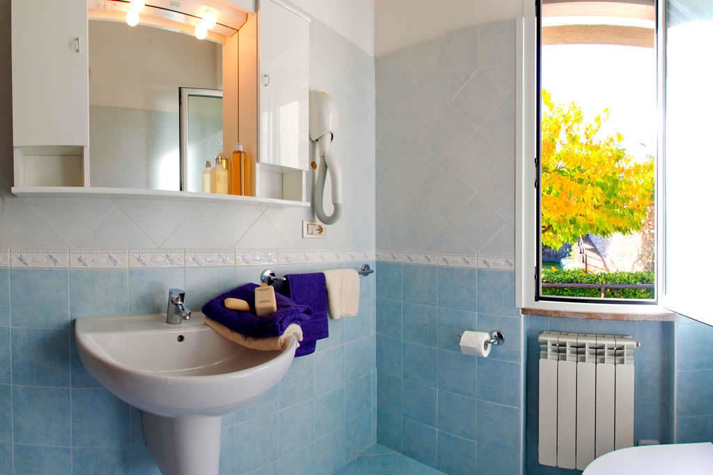 Un baño con lavamanos, espejo y ventana con vistas a árboles.