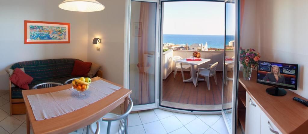 A balcony with a dining table, chairs, and a TV.