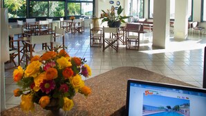 A hotel lobby with a reception desk, seating area, and large windows. - Residence Sant'Anna (Pietra Ligure)