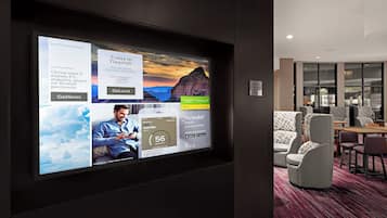 Un vestíbulo de hotel con una amplia pantalla digital que muestra noticias y anuncios de viajes.