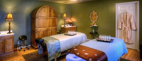 Une chambre avec deux lits, une armoire en bois, une coiffeuse avec un miroir et un peignoir accroché près de la porte.