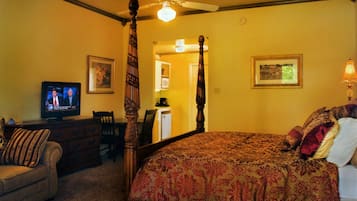 Um quarto com cama de dossel, televisão em uma cômoda e uma cadeira.