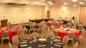 A conference room with multiple tables, each covered with a black tablecloth and surrounded by beige chairs.