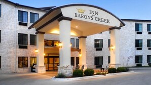 L’entrée d’un hôtel, avec une enseigne indiquant « INN ON BARONS CREEK », et une allée couverte bordée de colonnes.