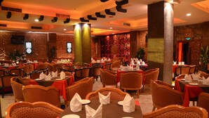 Ein Restaurant mit mehreren gedeckten Tischen, mit roten Tischdecken und ordentlich drapierten weißen Servietten.
