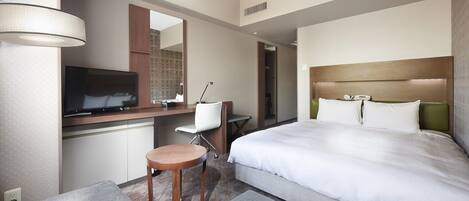 A hotel room with a bed, a desk with a chair, a television, and a mirror.