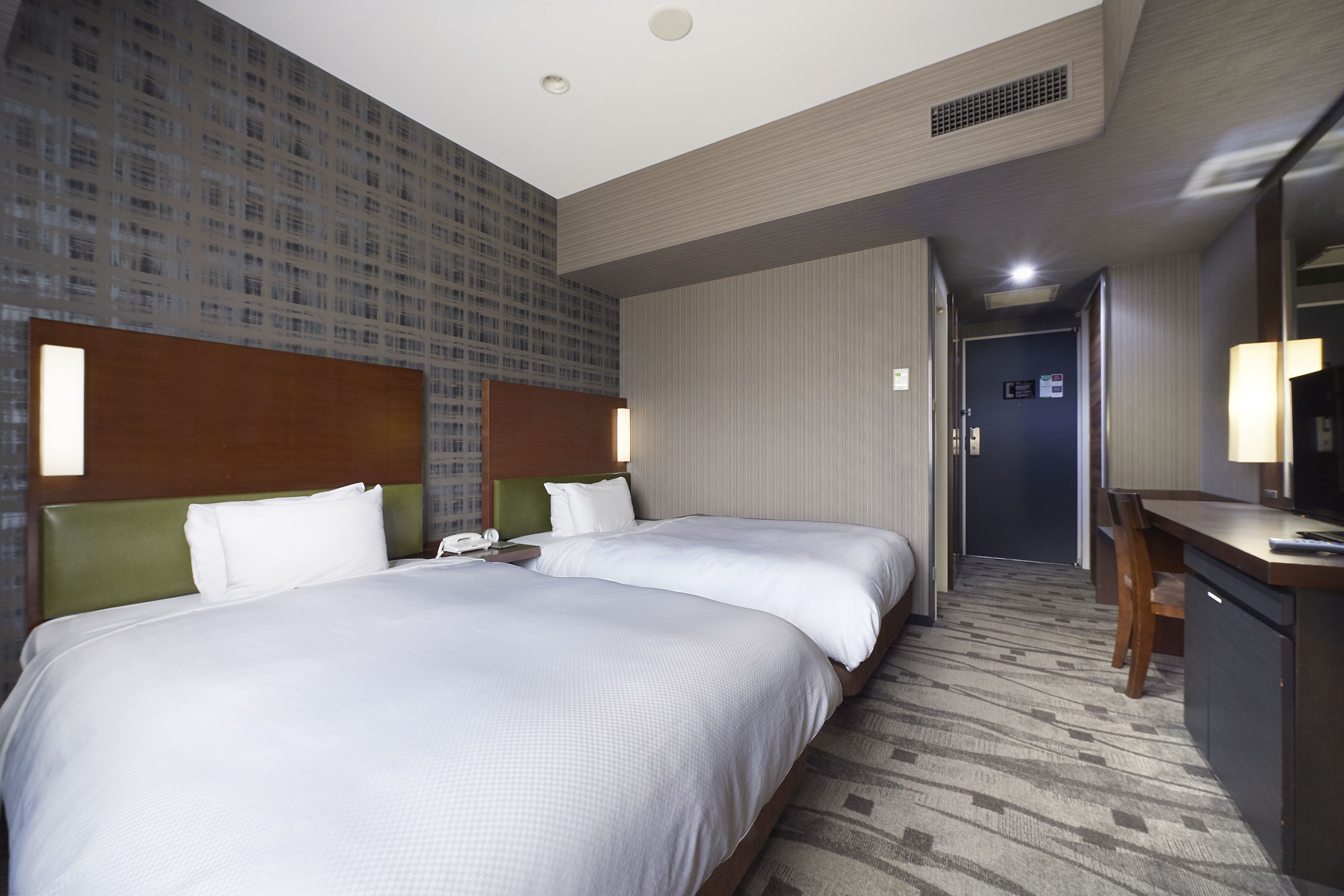 Une chambre d’hôtel avec deux lits, un bureau, une chaise et un téléviseur.