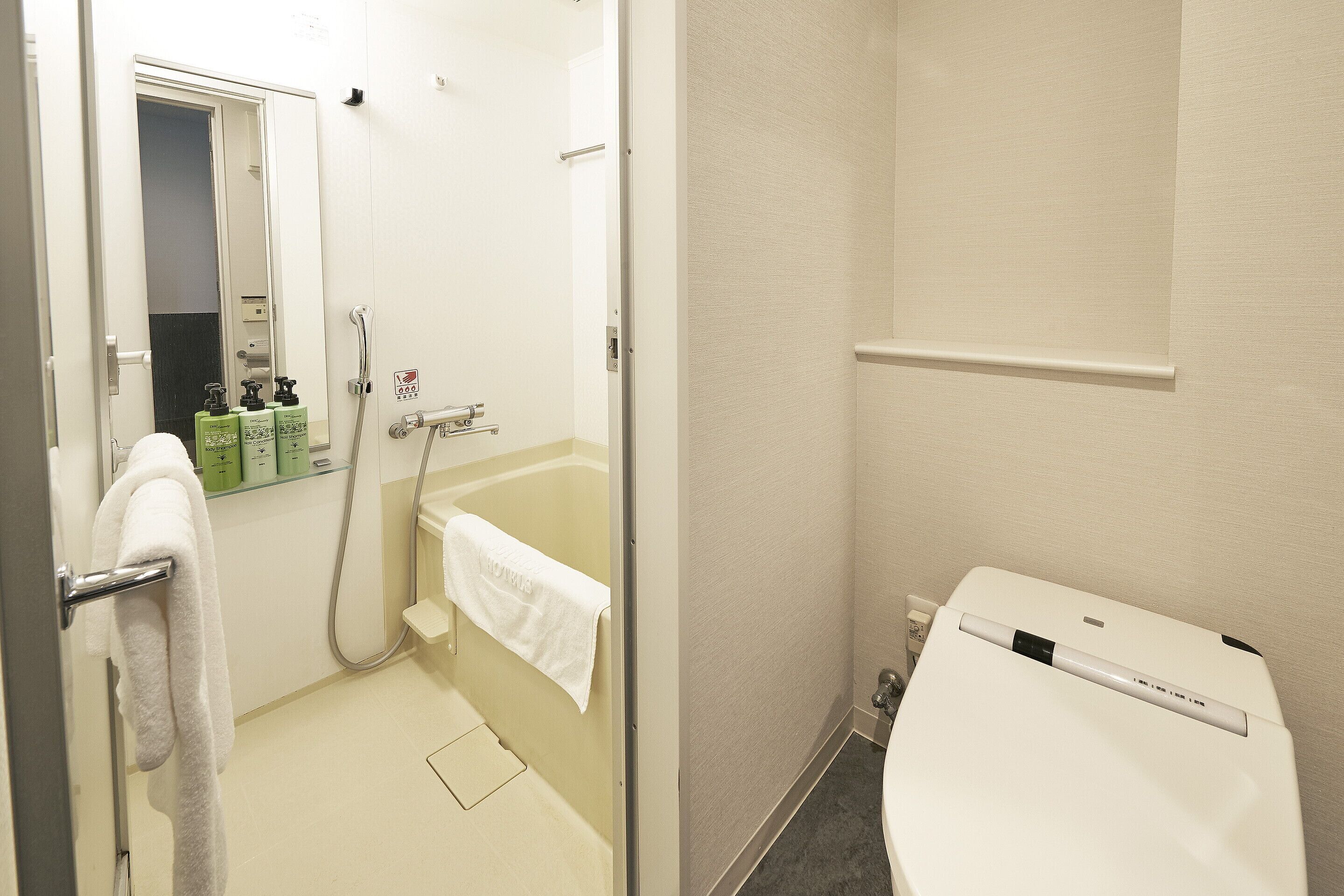Een badkamer met een bad, een toilet en een spiegel.