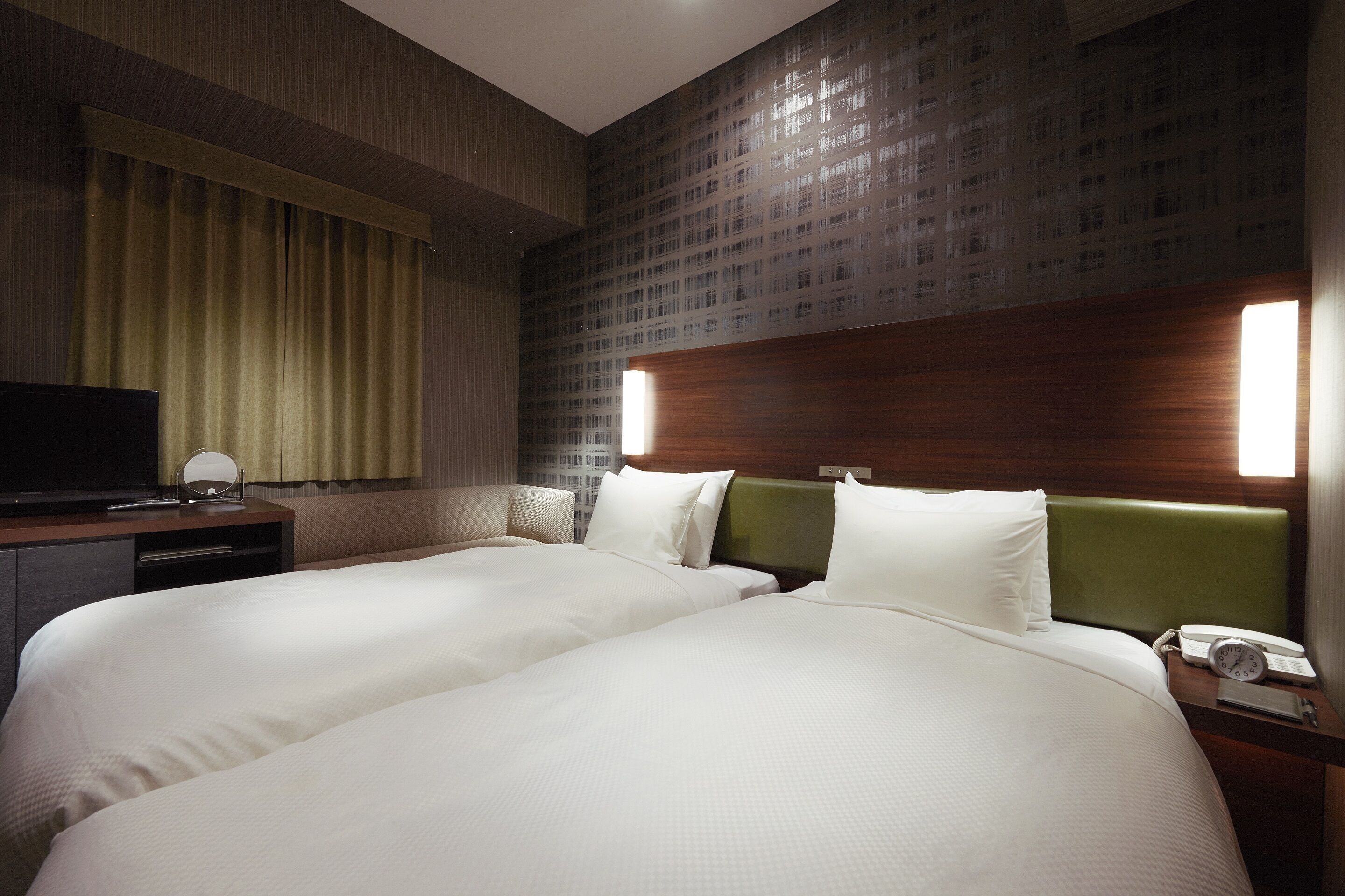 Ein Hotelzimmer mit zwei Betten, einem Fernseher, einem Schreibtisch und einem Telefon.