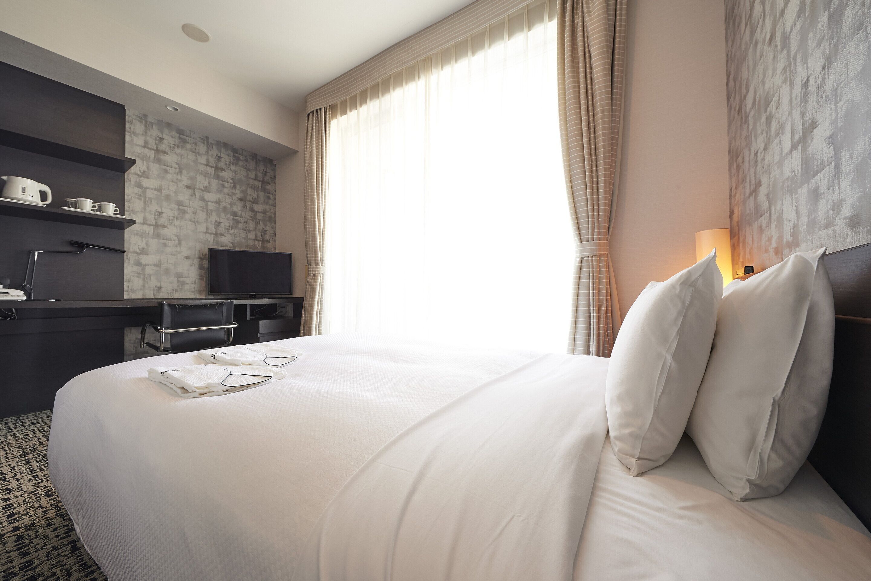 A hotel room with a large bed, a desk with a computer, and a TV.