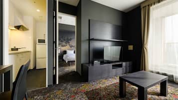 A modern hotel room with a flat-screen TV, a dining table, and a sofa.
