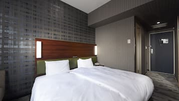A hotel room with a large bed, a wooden headboard, a green accent wall, and a patterned wallpaper.