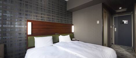 A hotel room with a large bed, a wooden headboard, a green accent wall, and a patterned wallpaper.