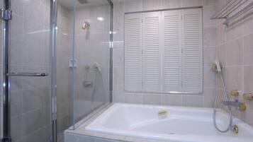 A modern bathroom with a glass-enclosed shower, a bathtub with a handheld showerhead, and a towel rack.