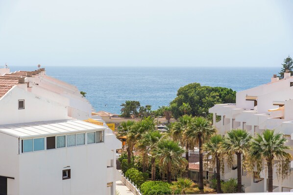 A coastal residential area with white buildings, palm trees, and a view of the sea. - Paloma Beach Apartments (Arona)