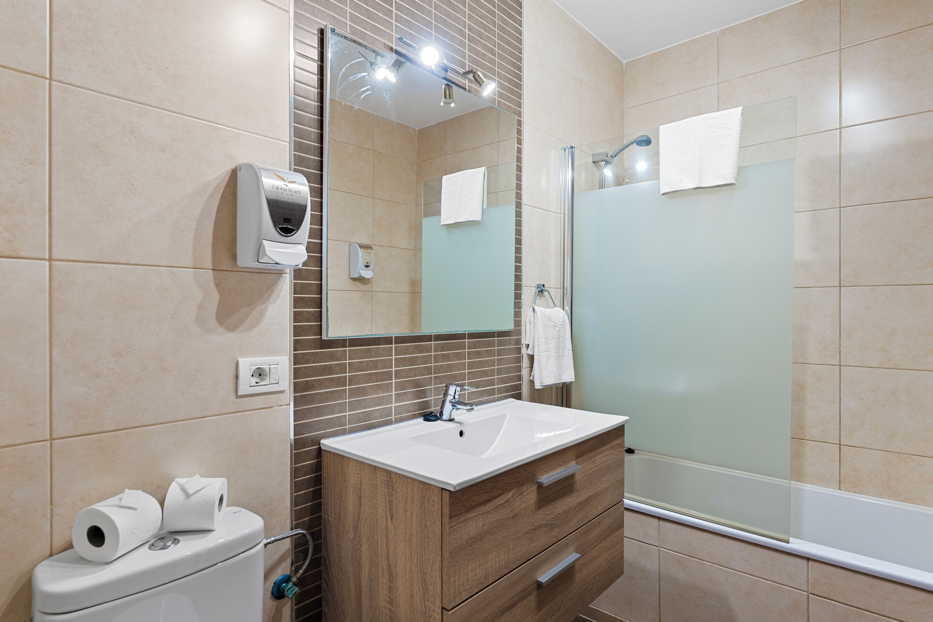 Un baño moderno con un espejo grande, un lavabo, un inodoro y una ducha.