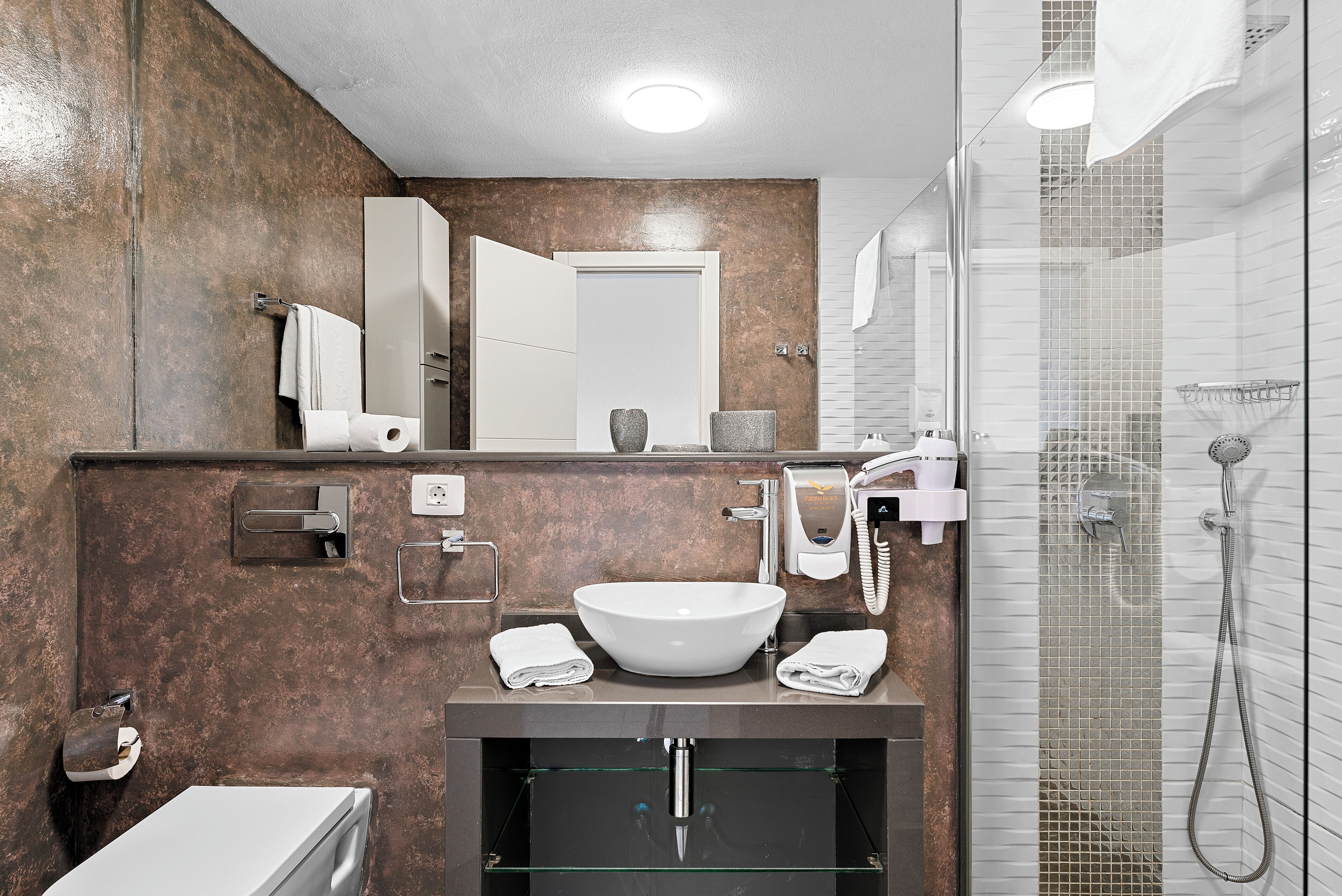 Un baño moderno con lavamanos grande, espejo y cabina de ducha de vidrio.