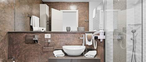 A modern bathroom with a large sink, mirror, and glass shower enclosure.