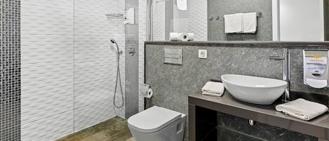 Een moderne badkamer met een douchecabine van glas, een witte wastafel en een toilet.