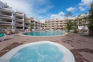 Una piscina al aire libre, sombrillas, sillones reclinables de piscina