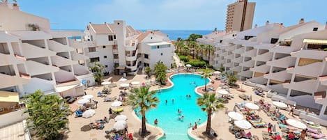 Una piscina al aire libre, sombrillas, tumbonas