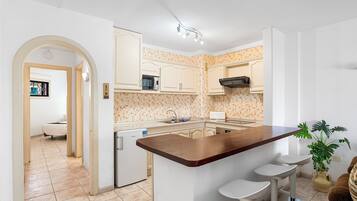 Una cocina con armarios blancos, una isla de madera con taburetes de bar, un microondas y un fregadero.