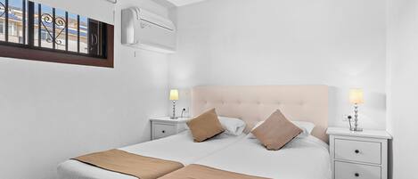 A double bed with two nightstands, each with a lamp, in a room with white walls and a ceiling fan.