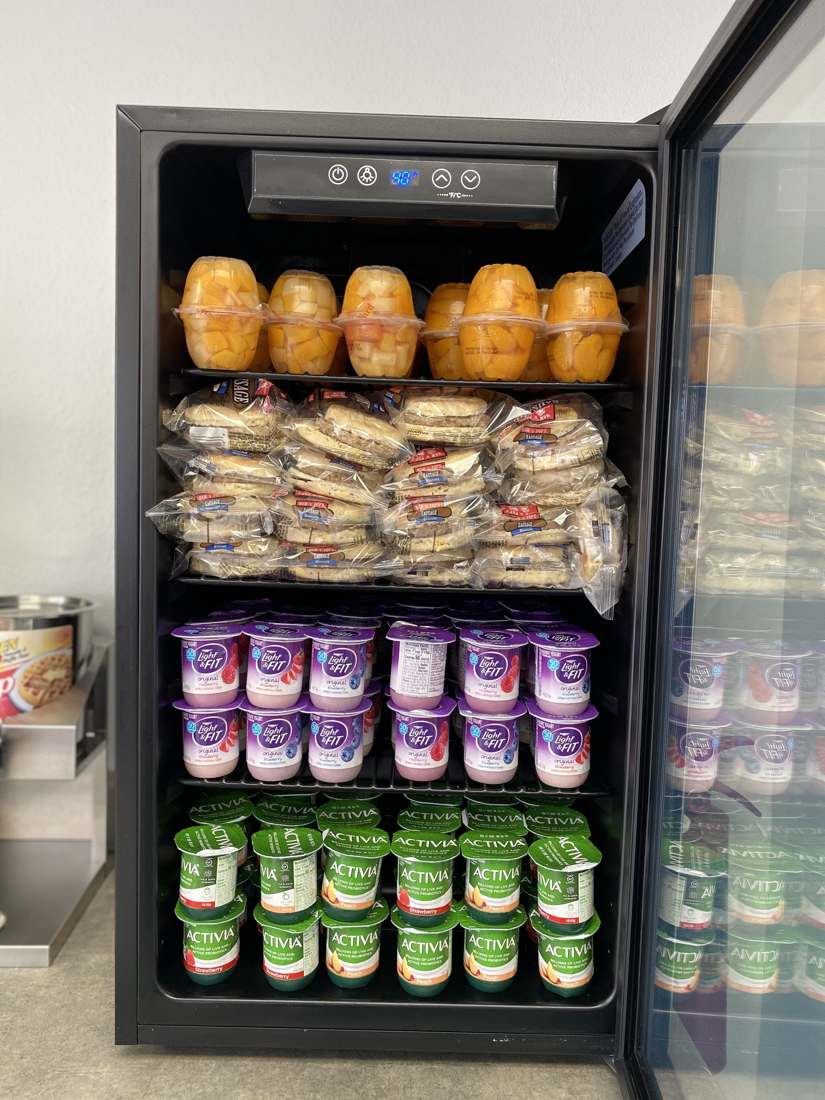 A refrigerated display case with various food items including packaged sandwiches, yogurt, and fruit.