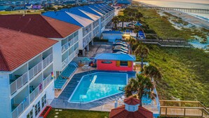 A hotel with a pool, multiple balconies, and a beach view. - The Islander Inn (Ocean Isle Beach)