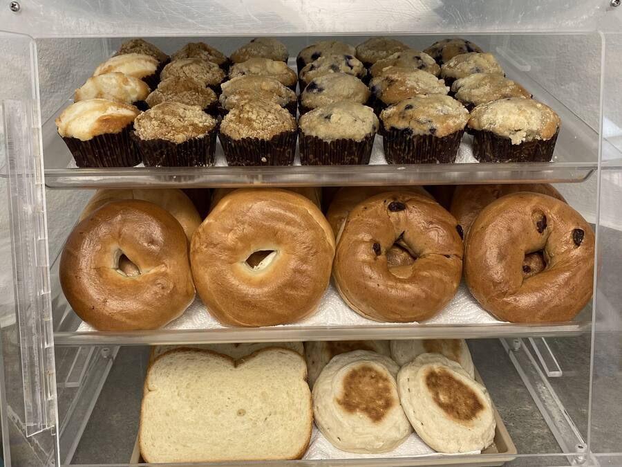 A bakery display case with muffins, bagels, and bread.