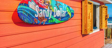 Un letrero colorido para Sandy Dollar Bar en un edificio de madera.