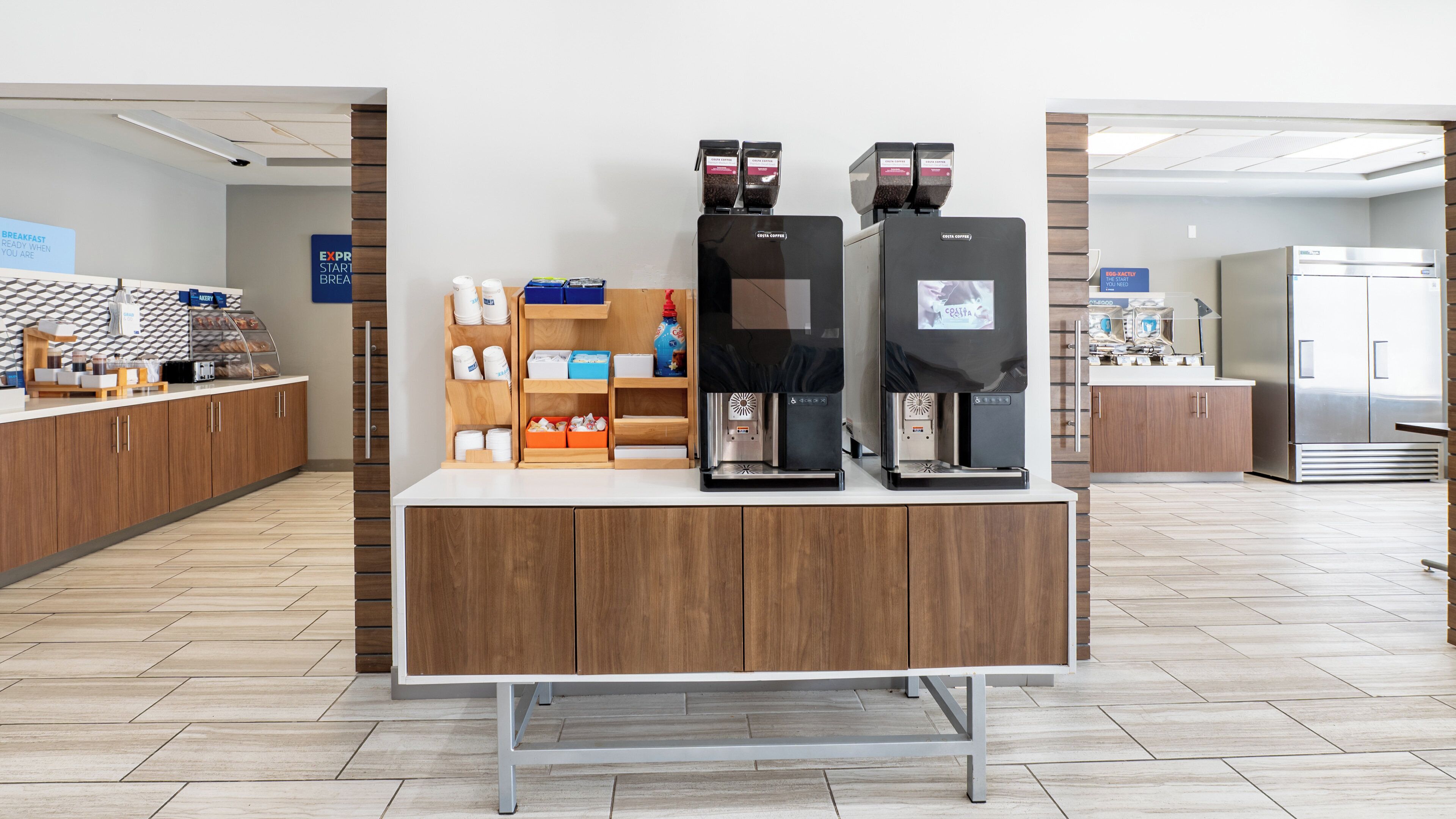 A coffee station with two espresso machines, a bread display, and a beverage dispenser.
